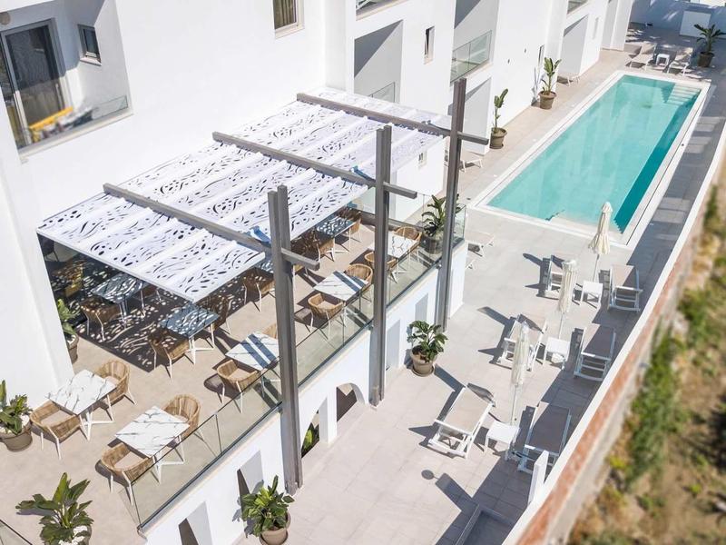 Nowoczesny basen hotelowy z leżakami i zadaszonym miejscem do siedzenia na tarasie.