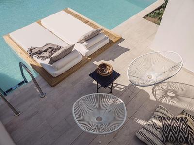 Moderne poolterras met witte stoelen en ligstoelen aan het water.