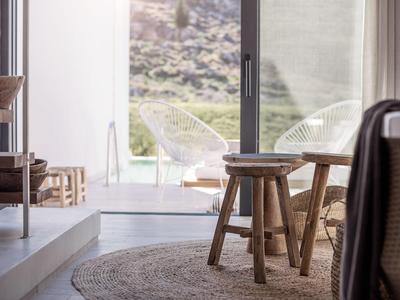 Gezellige interieur met houten meubels opent naar terras met stoelen en bergzicht.