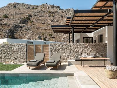 Area piscina moderna con lettini, ombrelloni e sfondo montano.