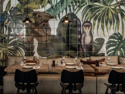 Accogliente zona pranzo con mosaico murale di animali e piante in un ristorante.
