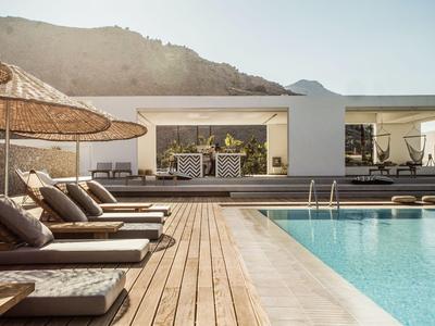 Piscina esterna moderna con lettini e vista su una villa vacanze elegante tra le montagne.