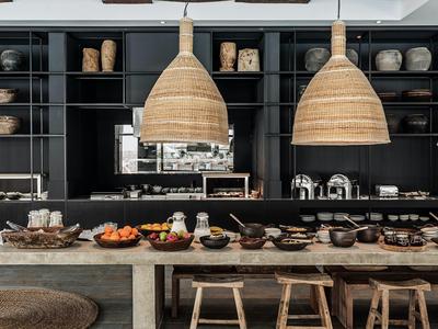 Moderne keuken met houten krukken, zwarte planken en grote geweven hanglampen.