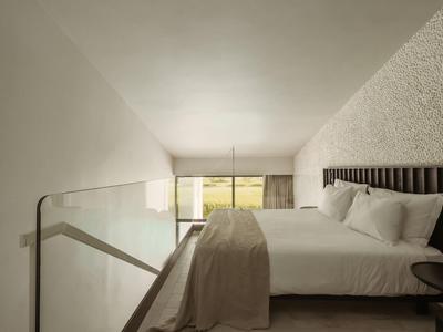 Moderne slaapkamer met groot bed en lichte, minimalistische inrichting met terraszicht.