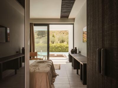 Slaapkamer met open deuren naar terras en uitzicht op tuin en natuur.