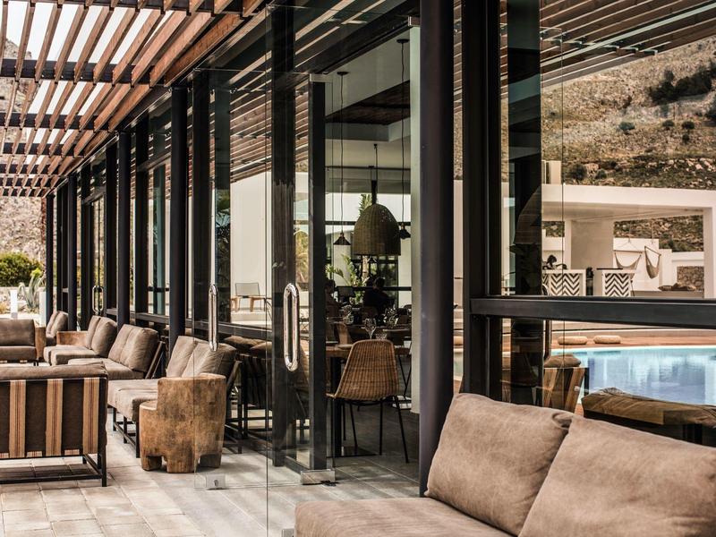 Gezellige lounge met moderne zitplaatsen op een terras naast een glazen gebouw.