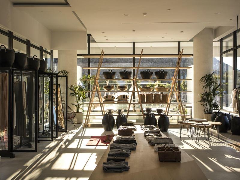 Lichte, moderne winkel met kleding en planten op planken en tafels weergegeven.