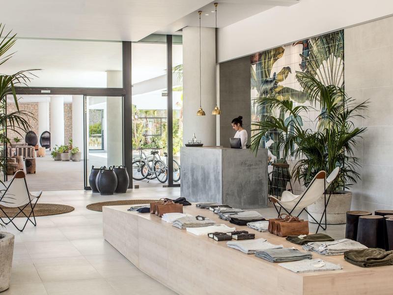 Moderne hotellobby met planten, zitplaatsen en elegant ontwerp in natuurlijk licht.