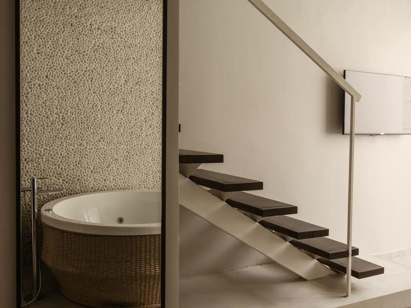 Modern spiegelkast reflecteert een rond bad naast een zwevende trap.