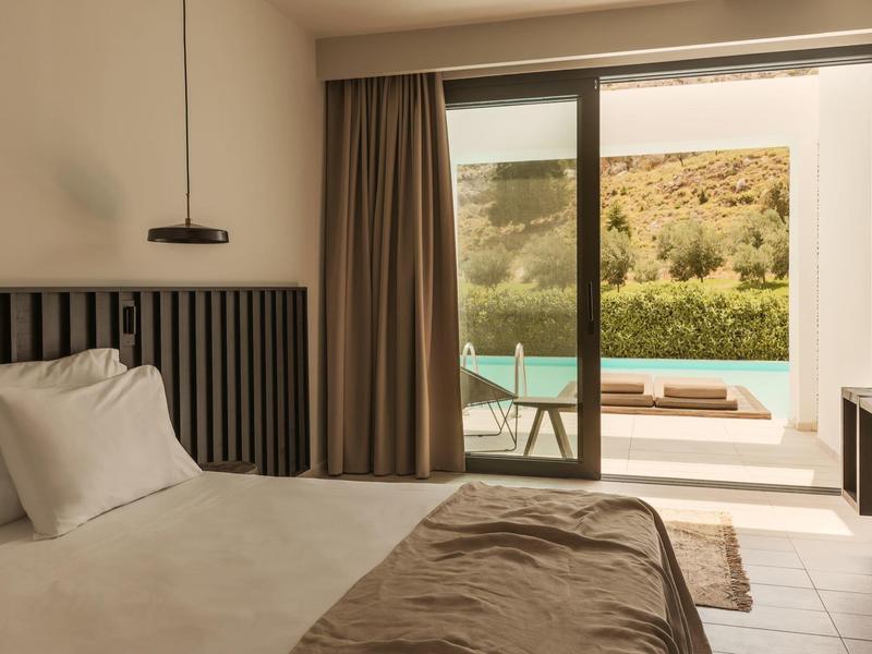 Modern hotelkamer met tweepersoonsbed en toegang tot terras met zwembad en natuurlandschap.