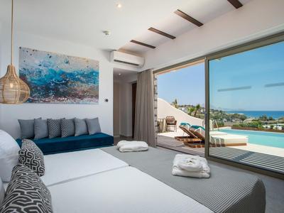Chambre moderne avec grandes fenêtres, vue sur piscine et mer.