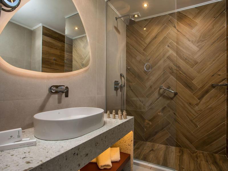 Salle de bain moderne avec lavabo rond et paroi de douche en bois à l'hôtel