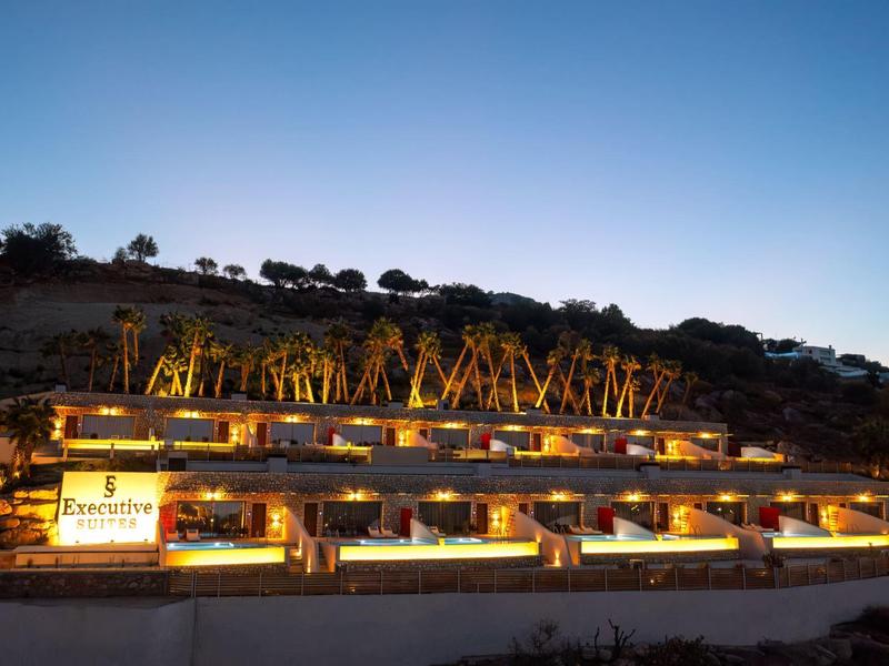 Complexe hôtelier moderne avec terrasses éclairées sur une colline au crépuscule