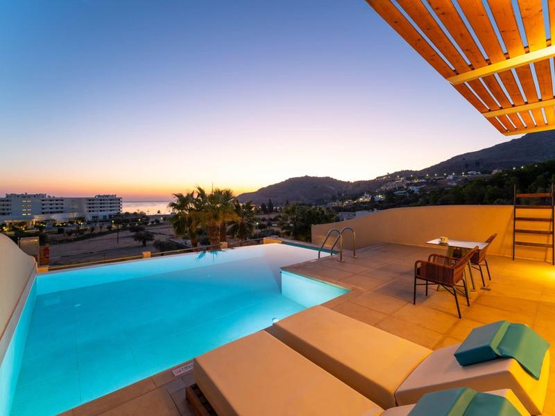 Chambre d'hôtel moderne avec piscine éclairée et transats au coucher du soleil