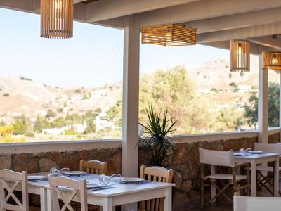 Überdachte Terrasse mit Holztischen und Stühlen mit Blick auf hügelige Landschaft.