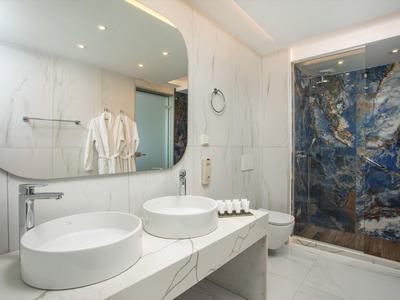 Nowoczesna łazienka hotelowa z dwoma okrągłymi umywalkami i prysznicem z niebieskiego marmuru.