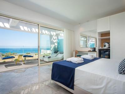 Modernes Schlafzimmer mit Meerblick, großem Bett und Balkon mit Sitzgelegenheiten.