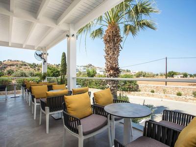 Zadaszony taras z stołami i krzesłami, widok na palmy i krajobraz