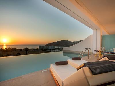 Basen infinity z leżakami i widokiem na zachód słońca nad morzem.