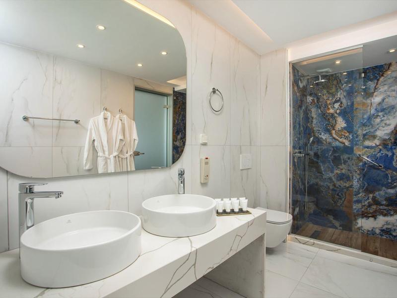 Nowoczesna łazienka hotelowa z dwoma okrągłymi umywalkami i prysznicem z niebieskiego marmuru.