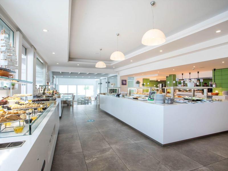 Jasna, nowoczesna sala śniadaniowa z bufetem i dużymi oknami w hotelu.