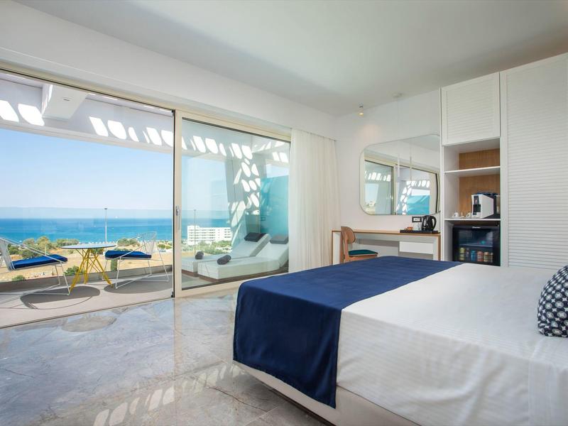 Nowoczesny pokój hotelowy z widokiem na morze i tarasem z miejscem do siedzenia.