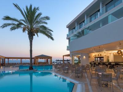 Nowoczesny basen hotelowy z palmami i miejscem do siedzenia o zachodzie słońca nad morzem.