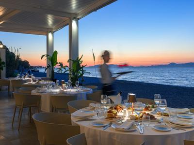 Terraza de hotel en la playa al atardecer con mesas preparadas y vista al mar.