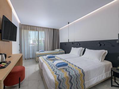 Habitación de hotel luminosa con dos camas individuales y luz moderna.