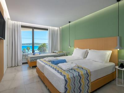 Habitación de hotel moderna con cama doble, vista al mar y decoración sencilla.