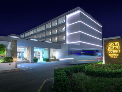 Edificio de hotel moderno con líneas iluminadas y entrada ajardinada por la noche.