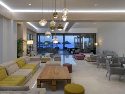 Jasny pokój hotelowy z żółtymi sofami, drewnianym stołem, nowoczesnym wystrojem i widokiem na zewnątrz.