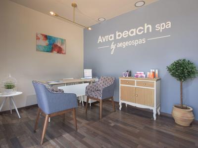 Heller Wellnessraum mit grauen Wänden, zwei Sesseln, Schreibtisch, Pflanze und Holzkommode.