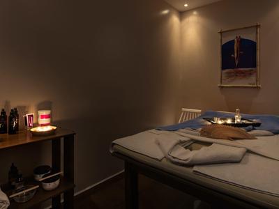 Gemütlicher Raum mit Massagetisch, weichem Licht und entspannter Atmosphäre.