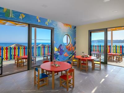 Kinderzimmer mit bunten Möbeln und Meeresblick durch große Fenster und Türen.