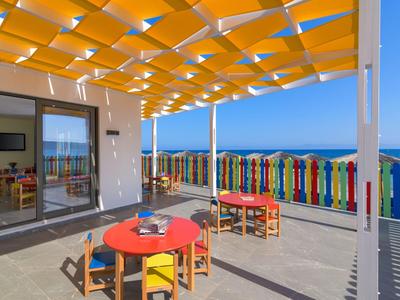 Terrasse mit bunten Stühlen und Tischen, Blick auf das Meer und bunte Zaunlatten