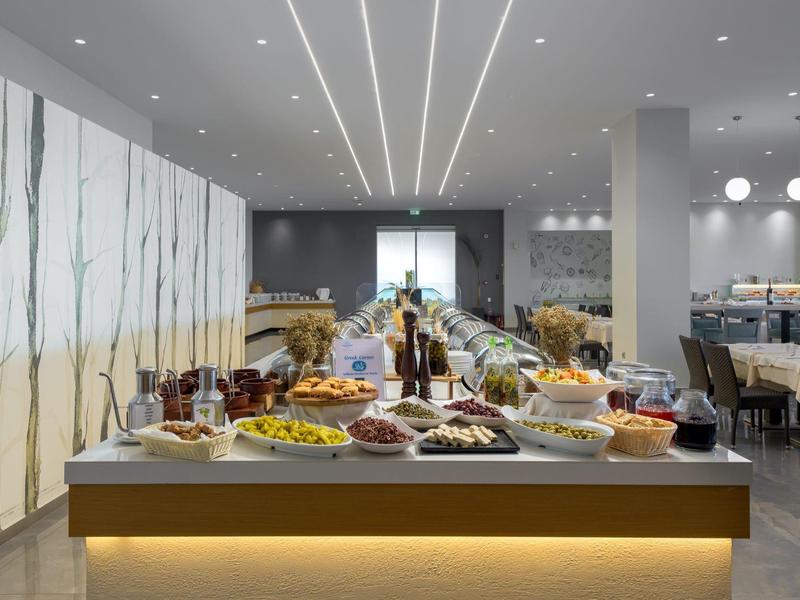 Ein Buffet mit vielfältigem Essen in einem modernen, hellen Speisesaal mit gedeckten Tischen.