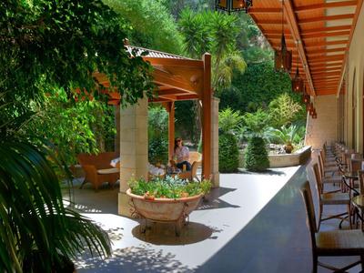 Hotel terrace with seating, lush plants, and sunshade.