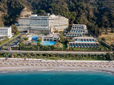 Luxury hotel with several buildings, pool, and direct access to the sandy beach by the sea.