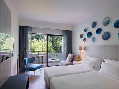 Bright hotel room with two beds, balcony, and modern wall accents.