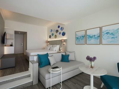 Modern hotel room area with white sofa, blue accents, and decorative wall art.