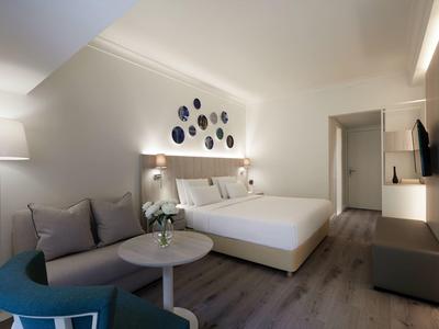 Modern hotel room with double bed, table, chairs, and wall decoration.