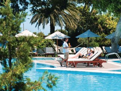 Hotelpool mit Liegestühlen, Sonnenschirmen und einem Kellner, der Getränke serviert.