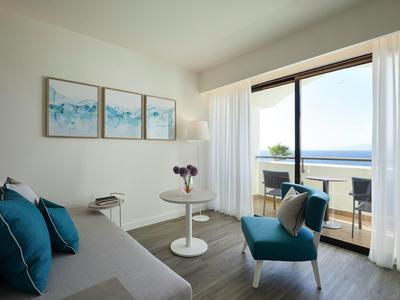 Bright hotel room with modern furniture and sea view from the balcony.