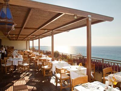 Überdachte Außenterrasse eines Restaurants mit Holzboden und Blick aufs Meer