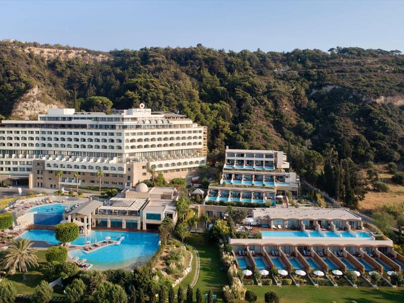 Large hotel resort with multiple pools in a wooded mountainous area.