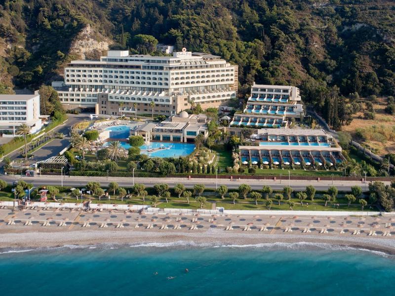 Luxury hotel with several buildings, pool, and direct access to the sandy beach by the sea.