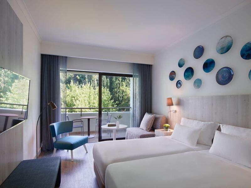 Bright hotel room with two beds, balcony, and modern wall accents.