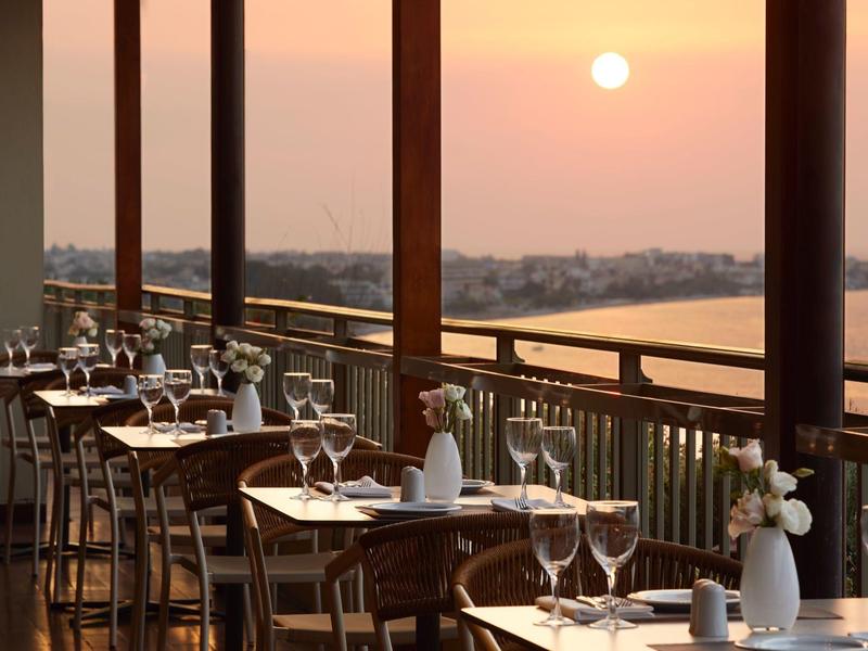 Terrace restaurant with set tables overlooking sunset over water
