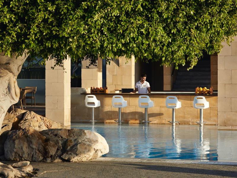 Pool bar with stools and bartender under trees on a sunny day